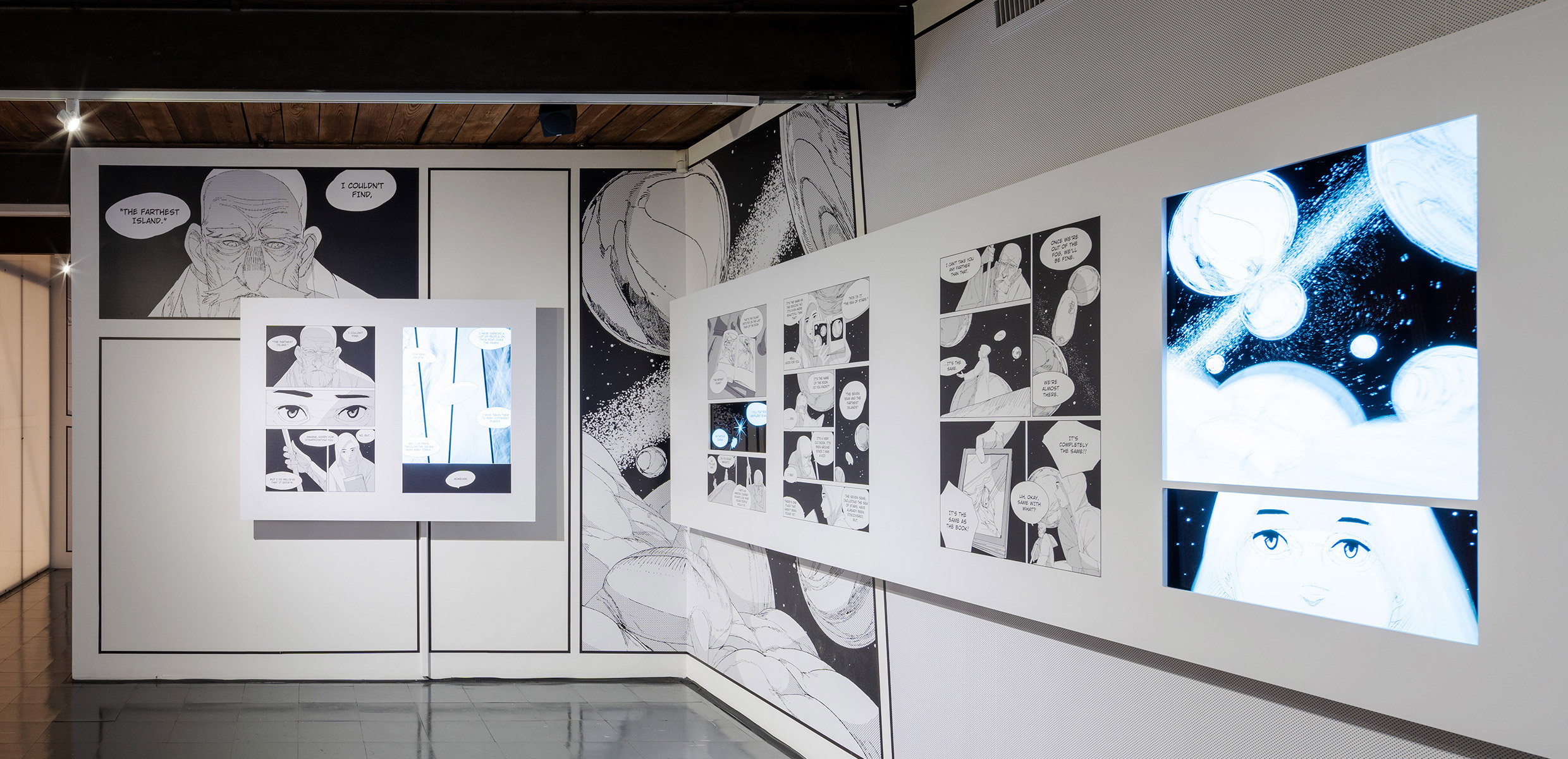 エキシビション会場内、平岡政展によるマンガ『案内人』の展示ゾーン。壁面には作品のグラフィックが大きく掲出され、その上にマンガが１ページずつ展示されている。ところどころマンガのコマにモニターが埋め込まれ、映像が映し出されている。