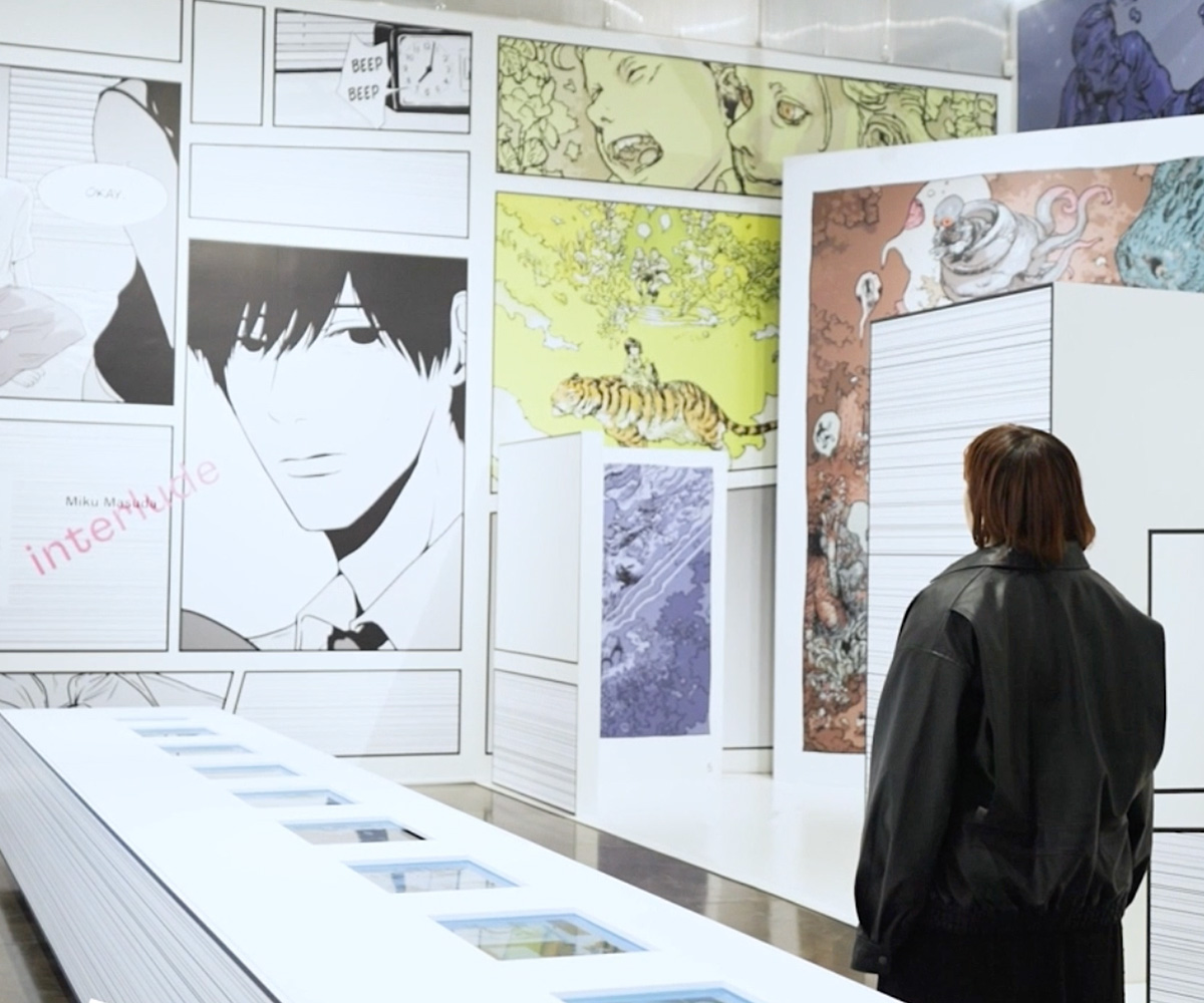 『Interlude』の作者・ますだみくが、同作品の展示ゾーンの壁面の前に立っている。