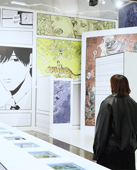 『Interlude』の作者・ますだみくが、同作品の展示ゾーンの壁面の前に立っている。