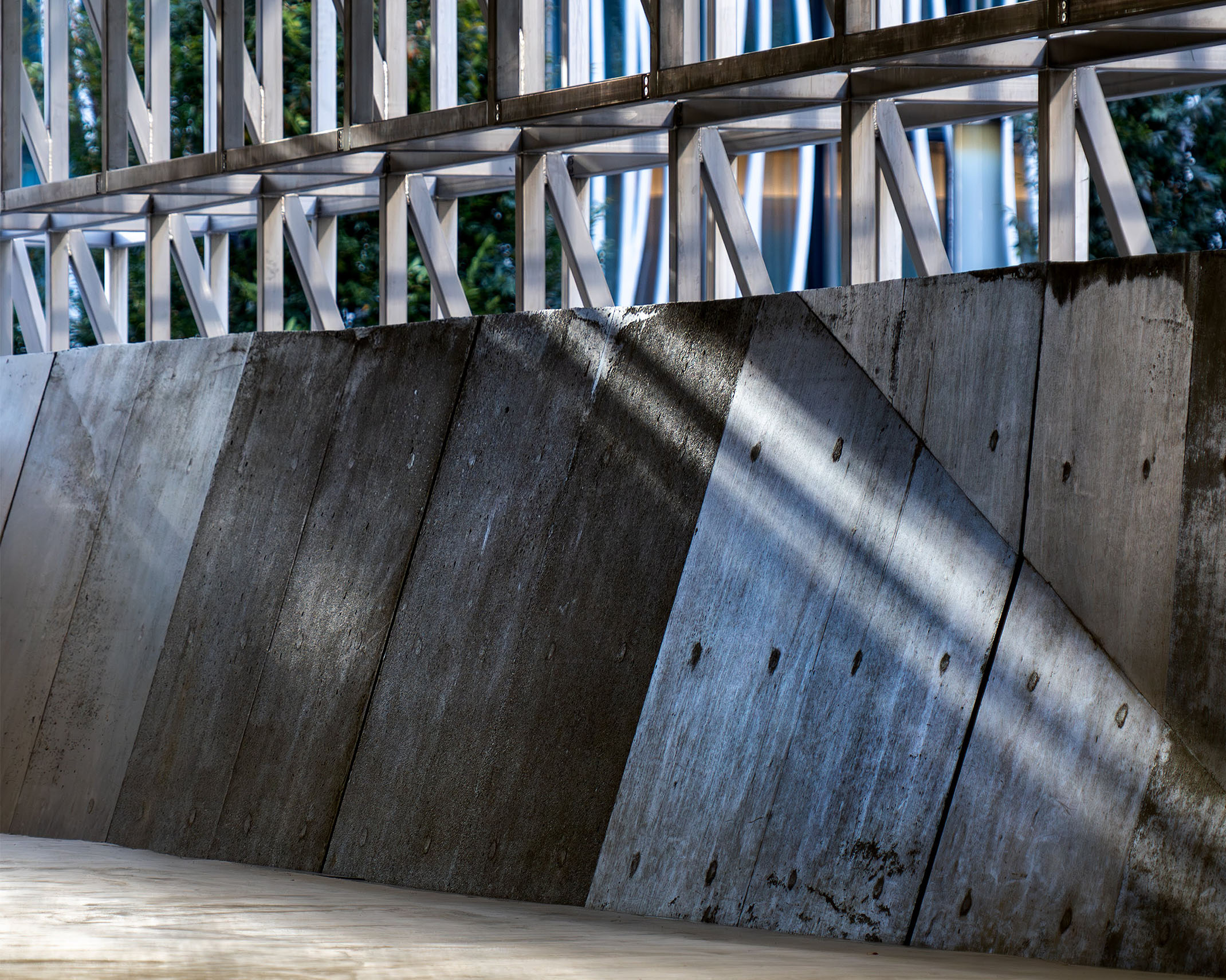 Ginza Sony Parkの2F通路。傾斜するコンクリート壁と金属フレームに、斜めの光が差し込み、建築のリズムが際立つ空間。