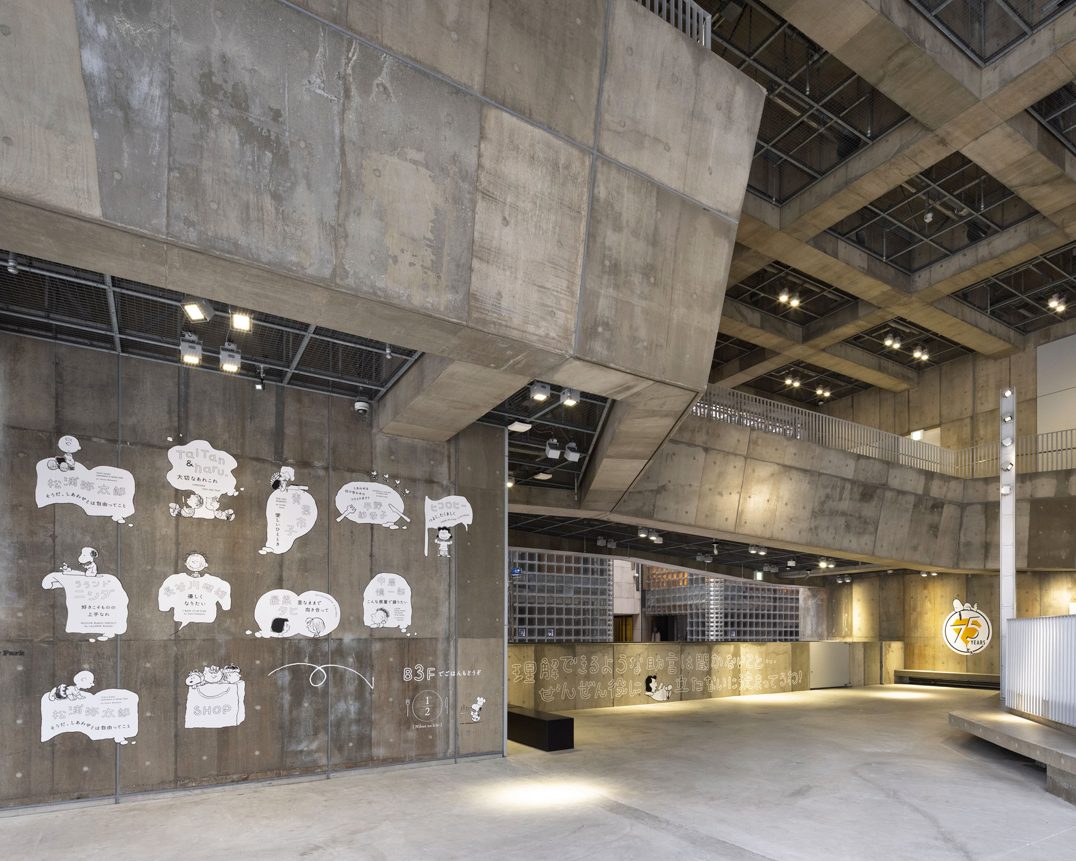 Concrete atrium space with Snoopy illustrations and messages displayed in white speech bubbles on the walls.