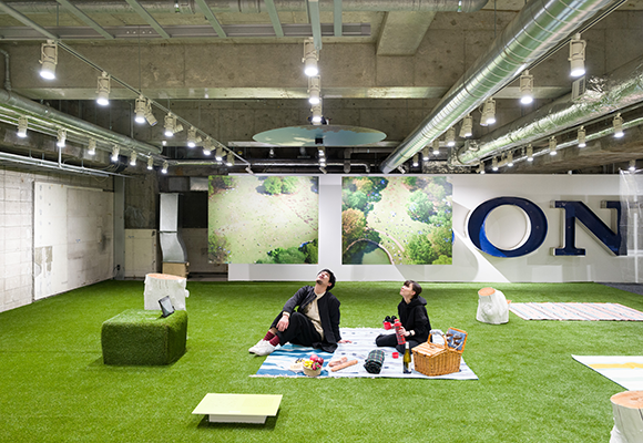 The “#005 PHOTO Playground – Meeting Photos, Playing with Photos” exhibition. A picnic on top of a grass lawn spread out on the basement floor