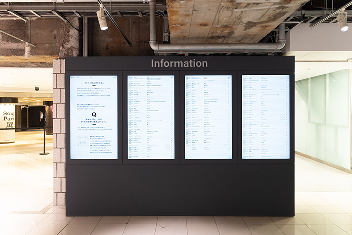 Three vertical signage monitor displaying the names of over 130 participating artists and the names of their songs