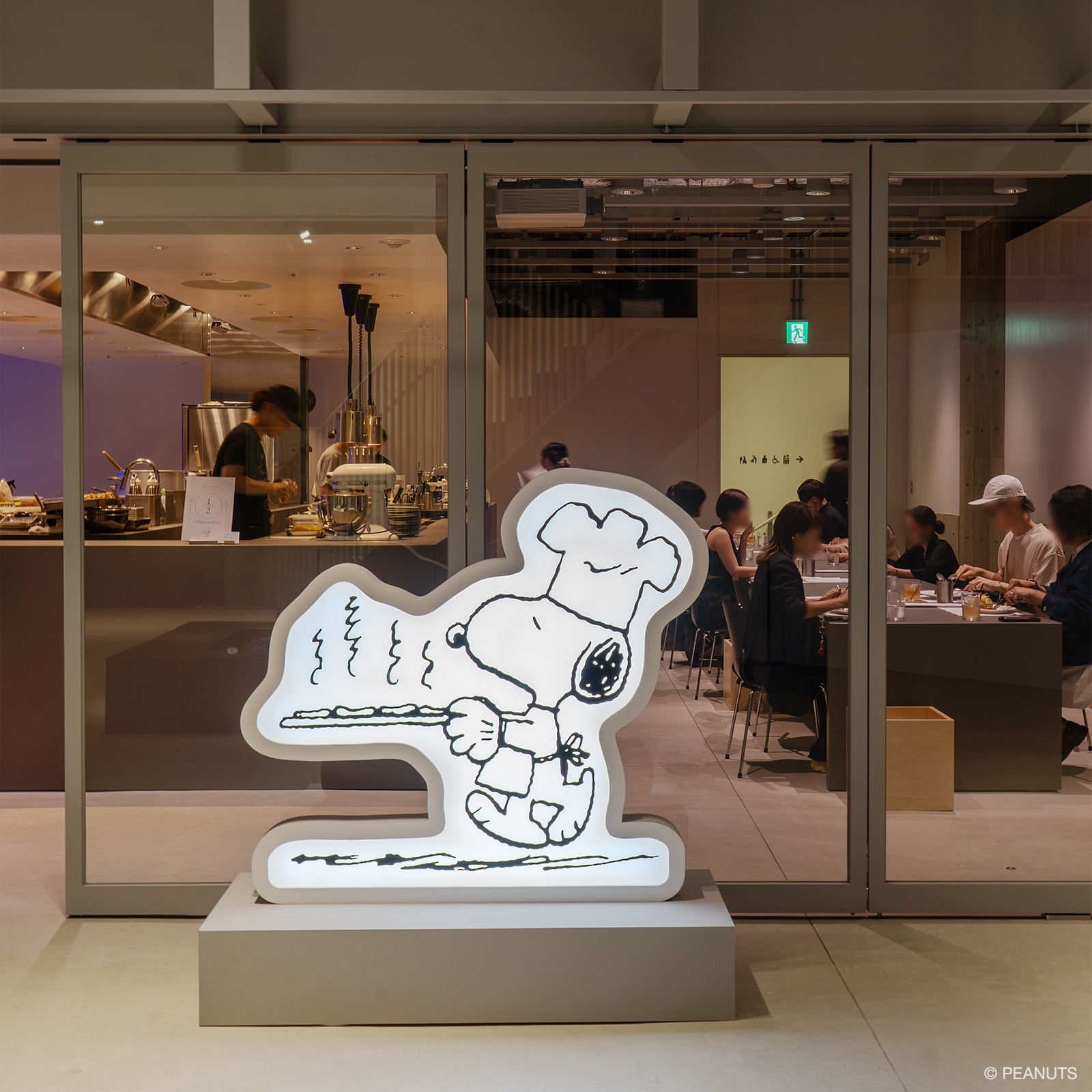 ガラス越しに見えるレストランの店内。入口前にはシェフの帽子をかぶり、食事を運ぶスヌーピーの行燈が設置されている。© PEANUTS