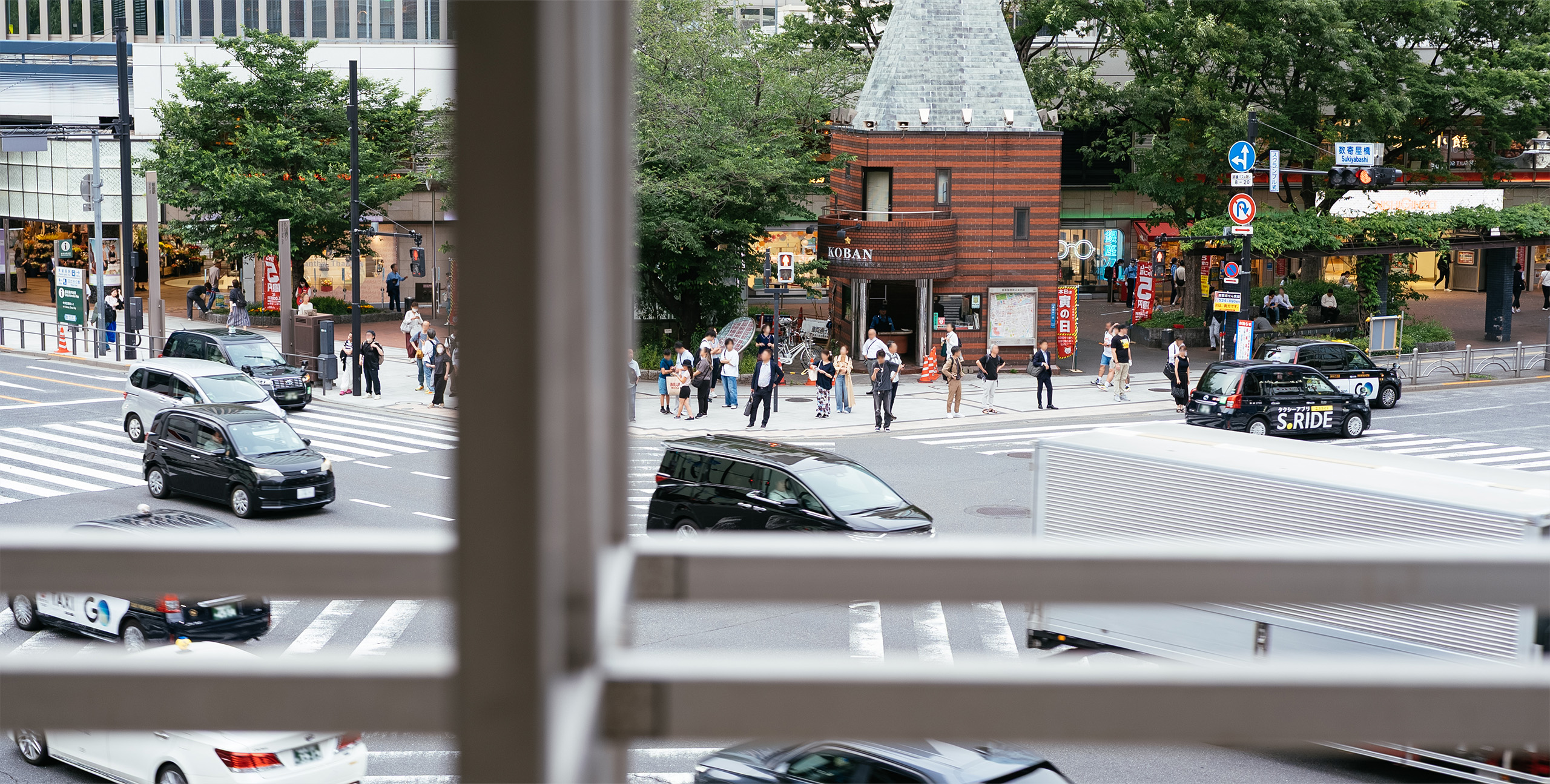 Ginza Sony Parkから見下ろした数寄屋橋交差点の風景。横断歩道や交番前に人々が立ち並び、車が行き交っている。
