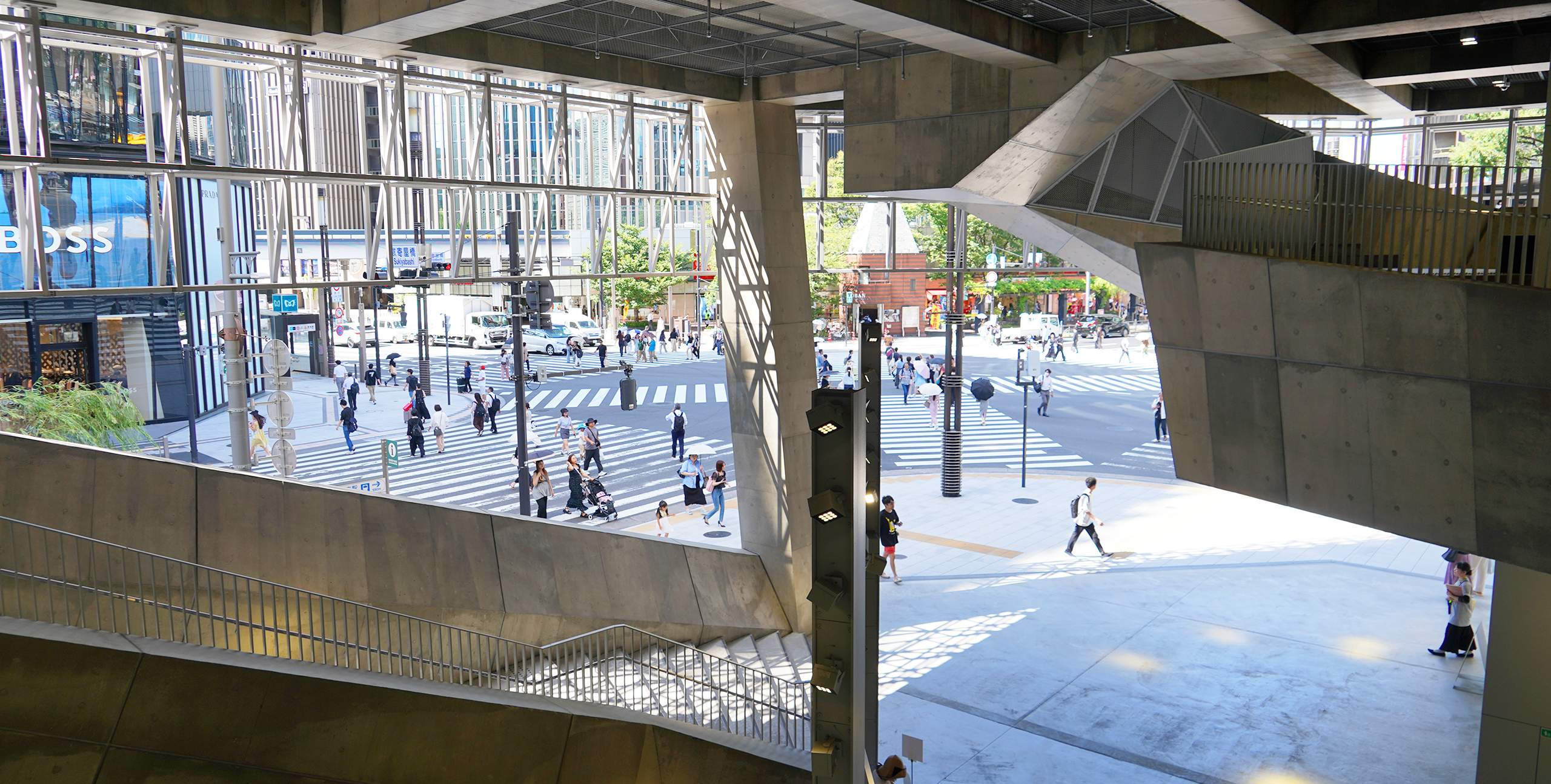 View of Sukiyabashi intersection from inside Ginza Sony Park, framed by concrete staircases and structures.