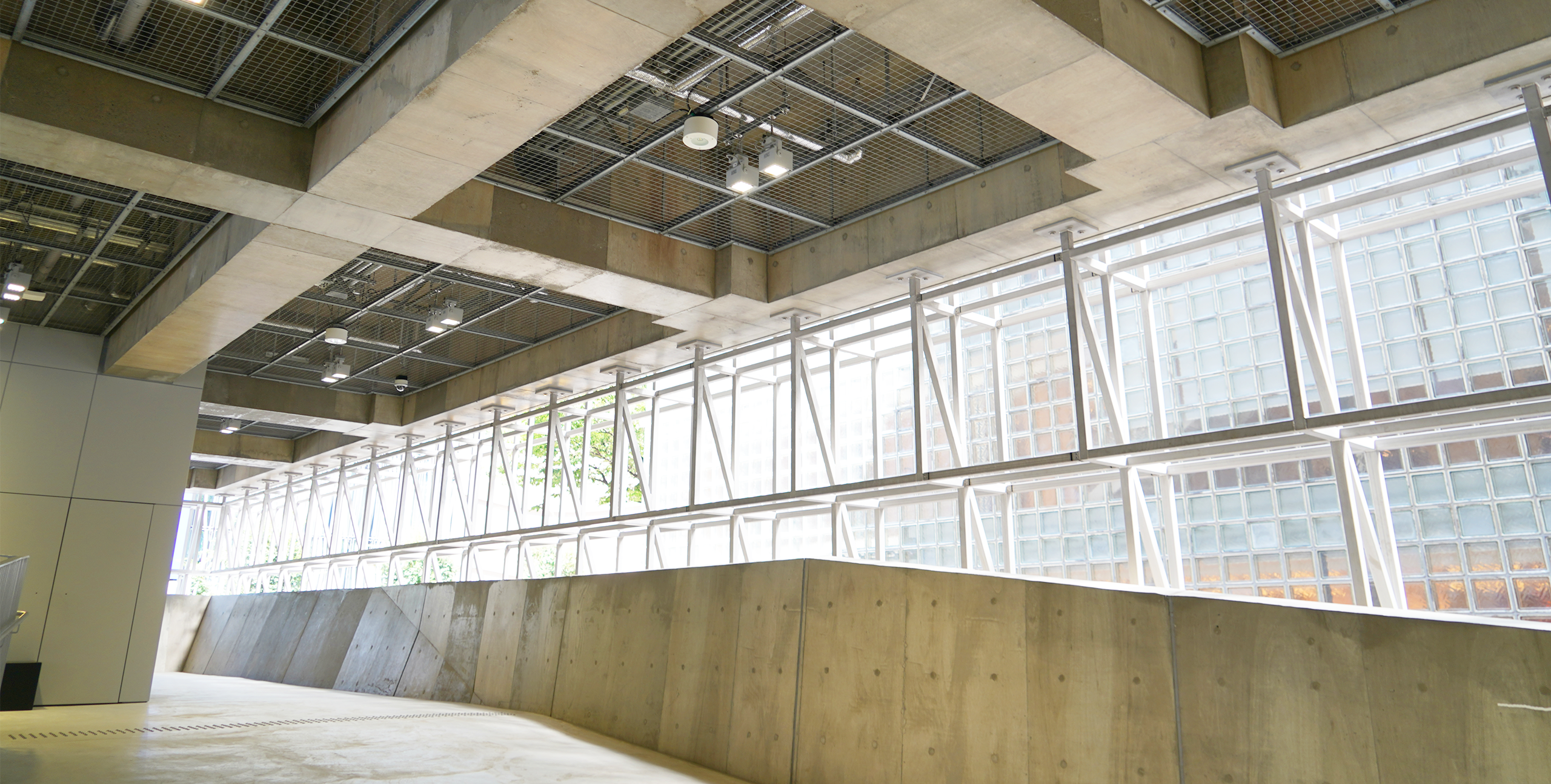 Concrete interior of Ginza Sony Park filled with natural light streaming through large windows framed with white lattice structures.