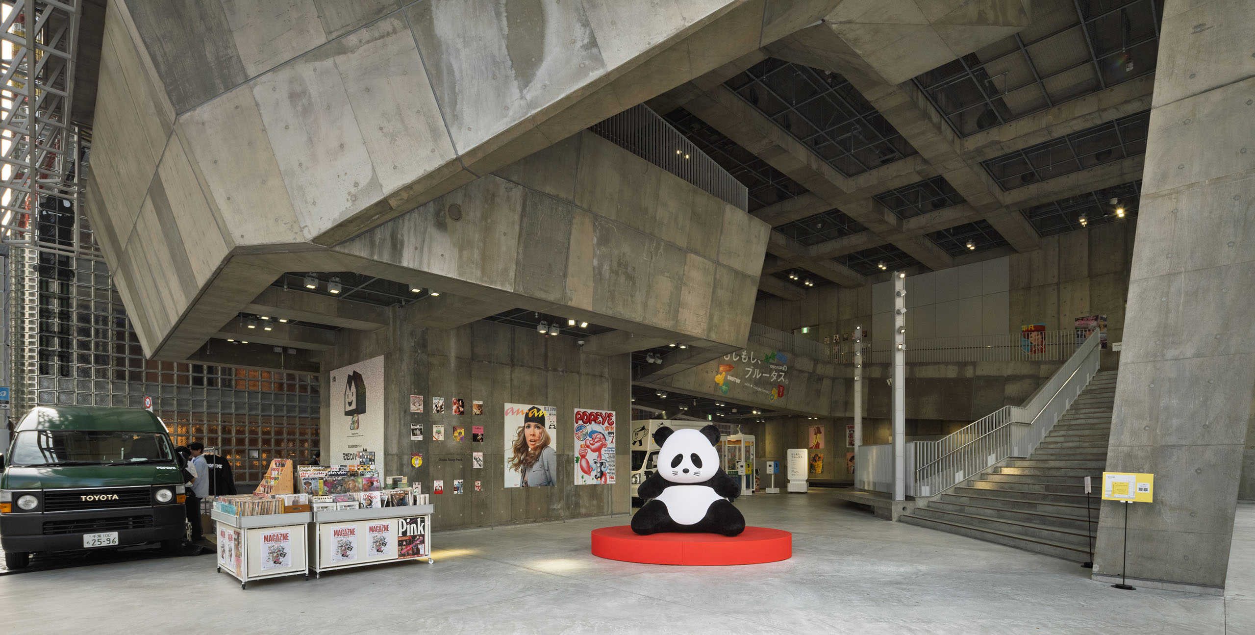 An atrium space near the entrance on the 1F of Ginza Sony Park features magazine covers lined up on a concrete wall, with “anan panda” sitting on a red pedestal in the center.
