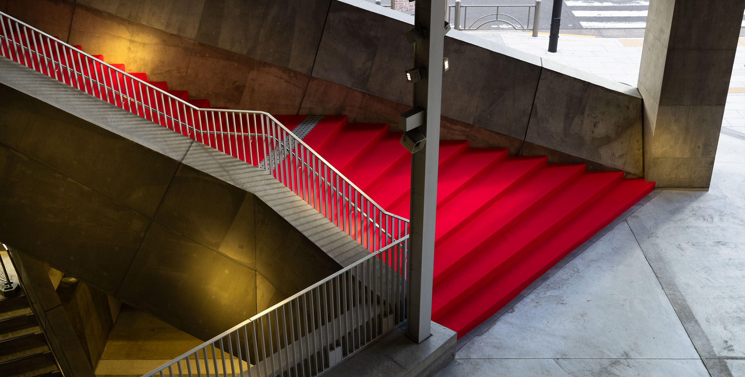 Ginza Sony Park館内の階段に敷かれたレッドカーペット。コンクリートの構造の中に鮮やかな赤が際立ち、外からの自然光が階段空間に差し込んでいる。