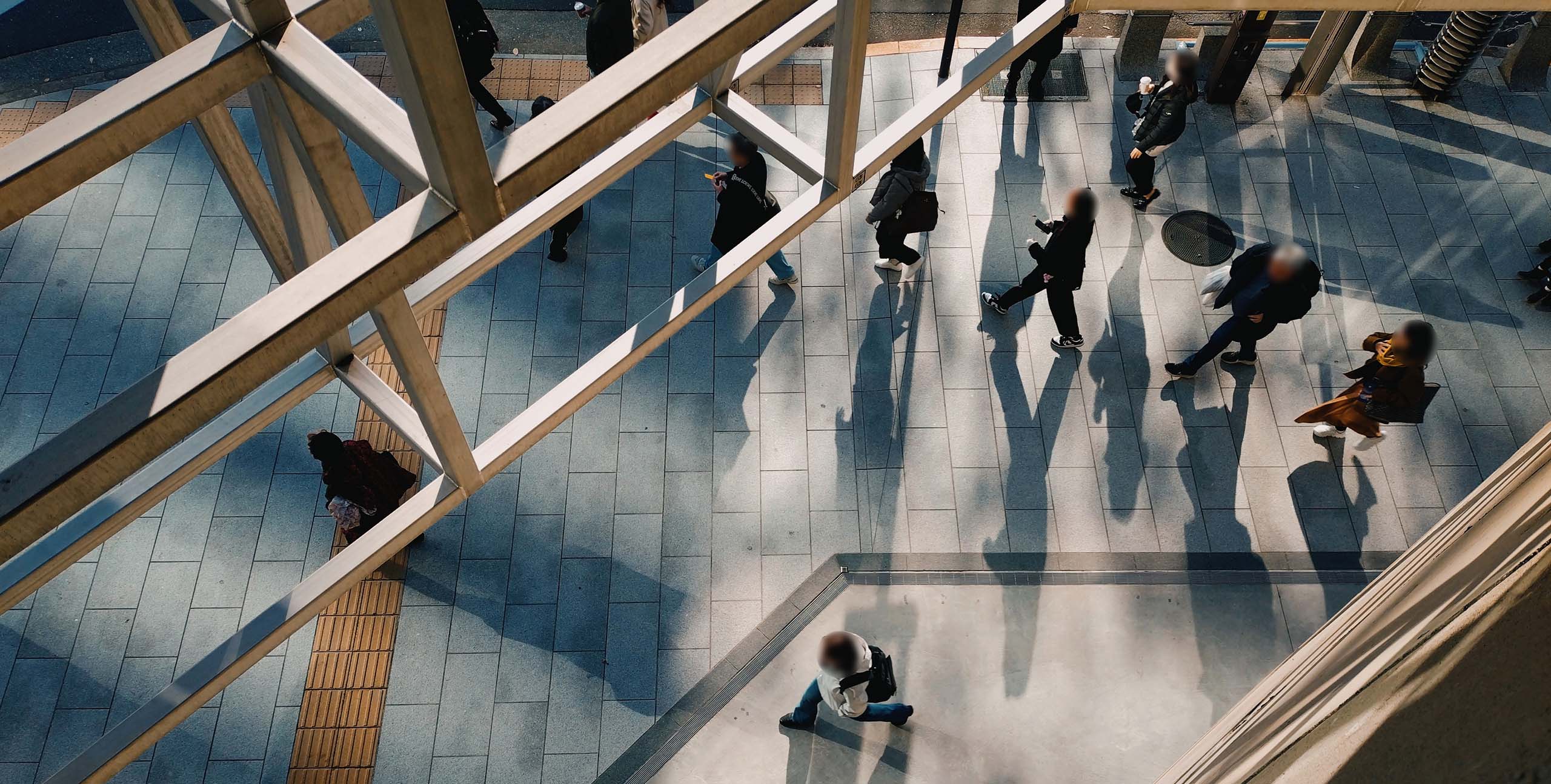 Ginza Sony Parの2Fから見下ろした通路を歩く人々。鉄骨の影が舗道に長く伸びている。