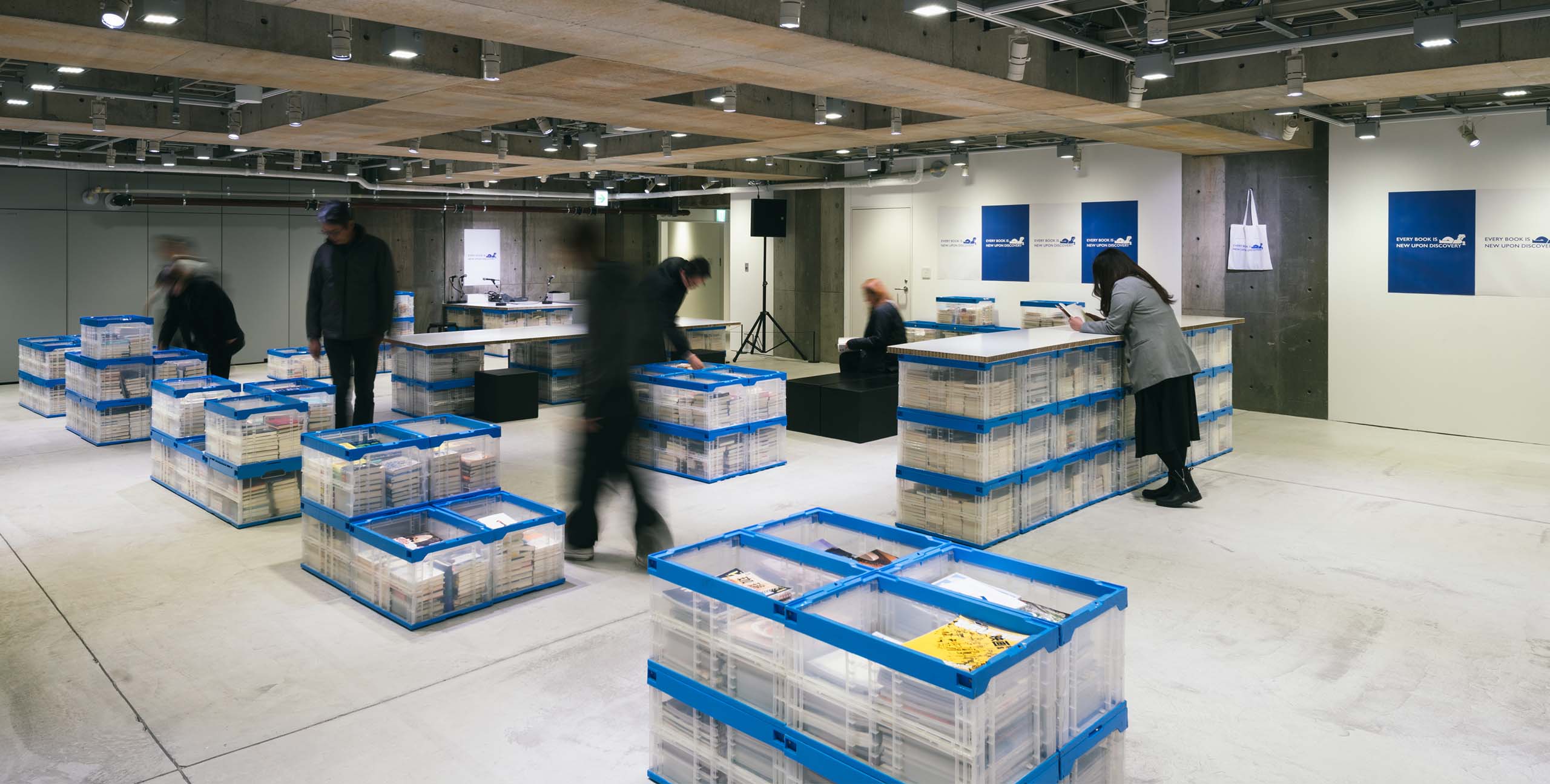 Ginza Sony Parkの空間に青いコンテナが並び、本が整然と収められている。来場者が行き交いながら、本との出会いを楽しむ。